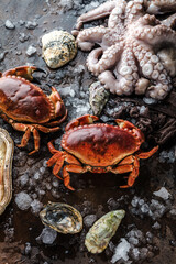 top view of delicious seafood with crabs, oysters, octopus, lemon slices, herbs and ice