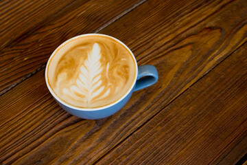 Latte coffee in a cup on a wooden table with copyspace.