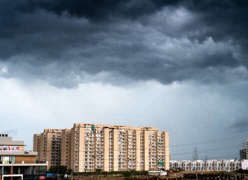 gurgaon delhi cityscape with monsoon clouds casting shadows on high rise apartments and buildings showing passage of time and rapid growth of real estate and infrastructure