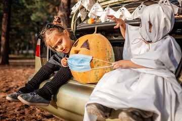 Safe distant Halloween celebration. Kids with decoration at themed party in the trunk of car