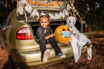Safe distant Halloween celebration. Kids with decoration at themed party in the trunk of car