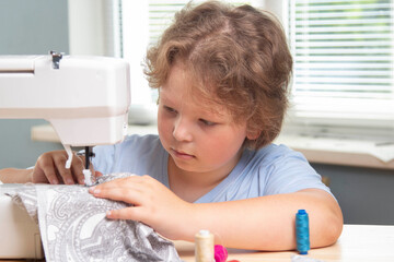 Boy using sewing machine at home to make crafts