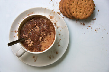 A bowl of milk with soluble cocoa and some cookies top view