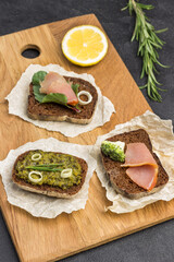 Appetizing bruschetta with various toppings on paper on board.