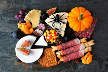 Halloween theme charcuterie board. Top down view against a dark background. Assortment of cheese...