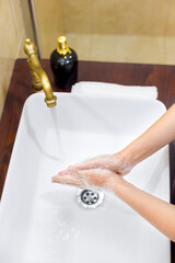 Woman washing and disinfecting hands with soap and hot water