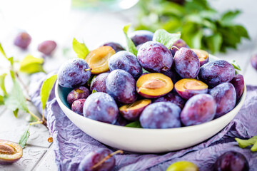 close-up view of bowl with fresh plums on table