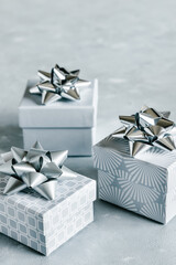 Christmas and New Year holiday monochrome background or greeting card. Gray gift boxes with silver bows. 