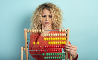 Girl with abacus is confused about the sum . cyan background - obrazy, fototapety, plakaty