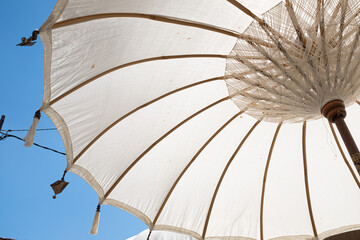 White sun umbrella on a solid blue sunny sky