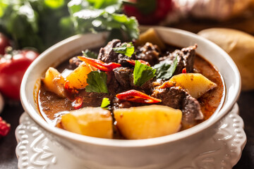 Bowl of goulash stew with meat, potatoes, chillies and parsley