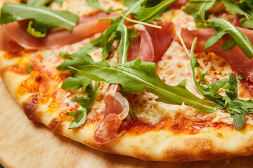 Delicious Italian Pizza with Parma ham and arugula, mozzarella cheese on dark background