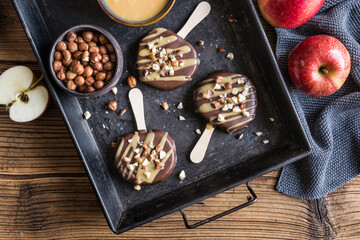 Apple popsicle dipped in chocolate and caramel, studded with hazelnuts