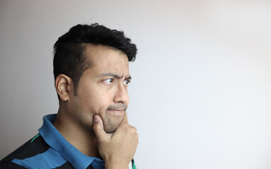 right side face of an asian man with inquisitive expression looking towards a copy space with white background.