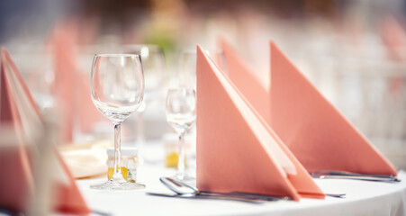 Pink napkins folded on a festive table with glassware and cutlery next to it