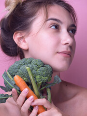 Fototapeta na wymiar Young woman bite big fresh broccoli carrot vegetable. Diet healthy eating concept isolated on pink background woman eating green broccoli. raw food. vegan food