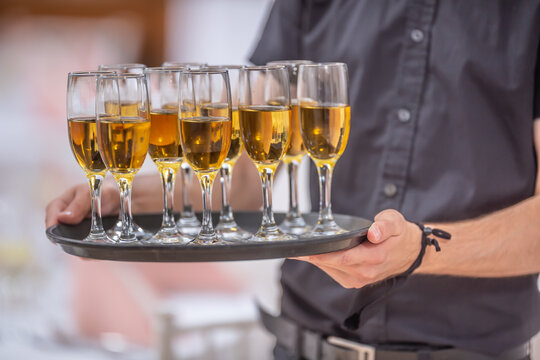 Waitor holding a serving tray full of drinks in champagne glasses