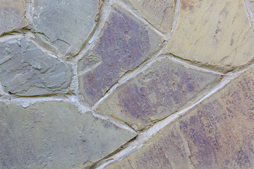 Texture of colorful stone wall with rough wide cement joints for background