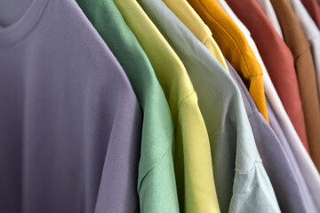 Colored clothes on hangers close up. Clothes hanging on shelf in store. Shopping