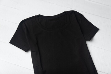 Black knitted t-shirt without pattern on white background. Mockup. Close up.