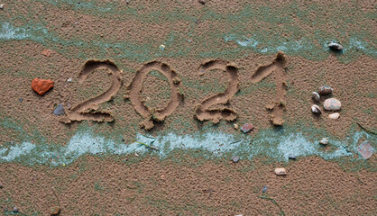 A small red stone - the heart and numbers of 2021 on the sand. Summer beach holidays . The message is handwritten.The concept of a New year