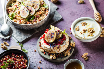 tasty healthy dish with figs fruits, nuts, honey, camembert cheese, couscous and pomegranate seeds...