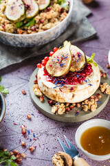 tasty healthy dish with figs fruits, nuts, honey, camembert cheese, couscous and pomegranate seeds and figs
