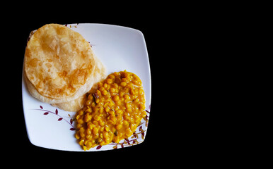 plate having luchi and cholar dal gram gravy on a plate in black background with space for text