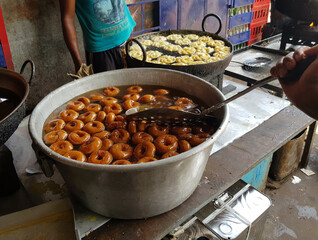 fried food vada dipped in sweet syrup in a big aluminium container