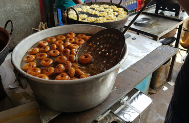 fried food vada dipped in sweet syrup in a big aluminium container