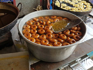 fried food vada dipped in sweet syrup in a big aluminium container