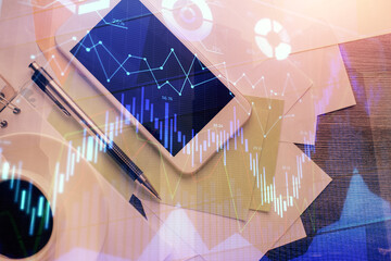 Multi exposure of forex graph hologram over desktop with phone. Top view. Mobile trade platform concept.