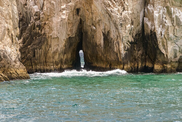 Cabo San Lucas, Mexico - April 22, 2008: South end of Baha California. Closeup of vertical  see-through slit in beige rocks formation. Greenish ocean water in front.