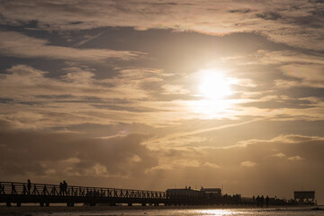 People on wooden seabridge at north sea beach in Sankt Peter-Ording, Germany.