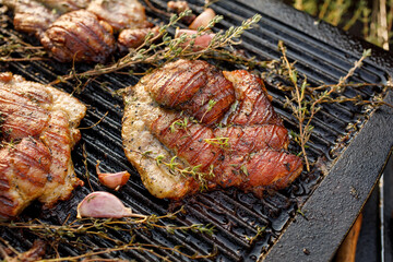 Grilled pork neck with herbs and garlic on a cast iron grill plate, close-up view