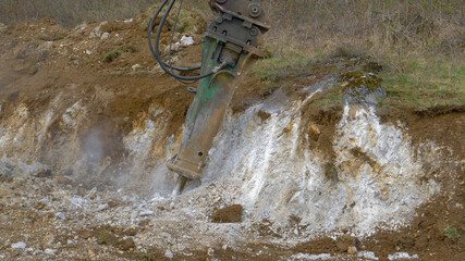 CLOSE UP: Jackhammer excavator attachment crushes rocks during construction