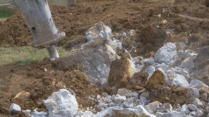 CLOSE UP: Big breaker hammer demolishes rocks during roadworks in countryside.