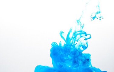 Closeup of a blue ink in water in motion isolated on white. Ink swirling underwater. Colored abstract smoke explosion effect. Abstract background with copy space..