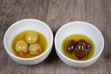 White Bowls with green and black olives on wooden table top views