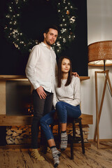 Obraz premium New Years concept, man and woman celebrate Christmas together in an interior decorated with garlands and a fireplace