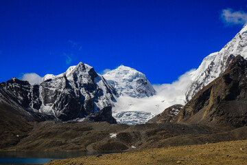 Landscape of deep blue sky and ice capped peaks of himalayan mountains with white clouds during day time