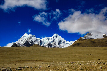 Fototapeta premium Landscape of deep blue sky and ice capped peaks of himalayan mountains with white clouds during day time