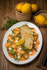 Salmon carpaccio on a plate with lemons, arugula, goat cheese and croutons
