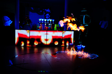Professional barman and led light fire show. Silhouette of modern bartender shaking drink at night cocktail bar.