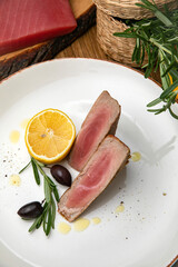 Salmon carpaccio on a plate with lemons, arugula, goat cheese and croutons
