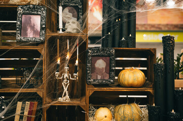 Close photo of Halloween scenery with cobwebs in the web, candles, pumpkins, old photo frames and...