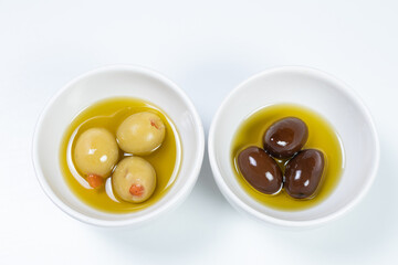 Black and green olives in a small casserole with olive oil on a white surface background