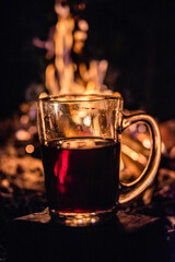 Transparent glass with a drink on the background of fire. Grain and Noise vintage edition.