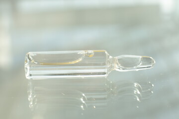 A glass vial with a solution lies on a glass table