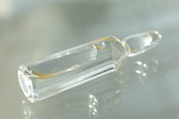 A glass vial with a solution lies on a glass table